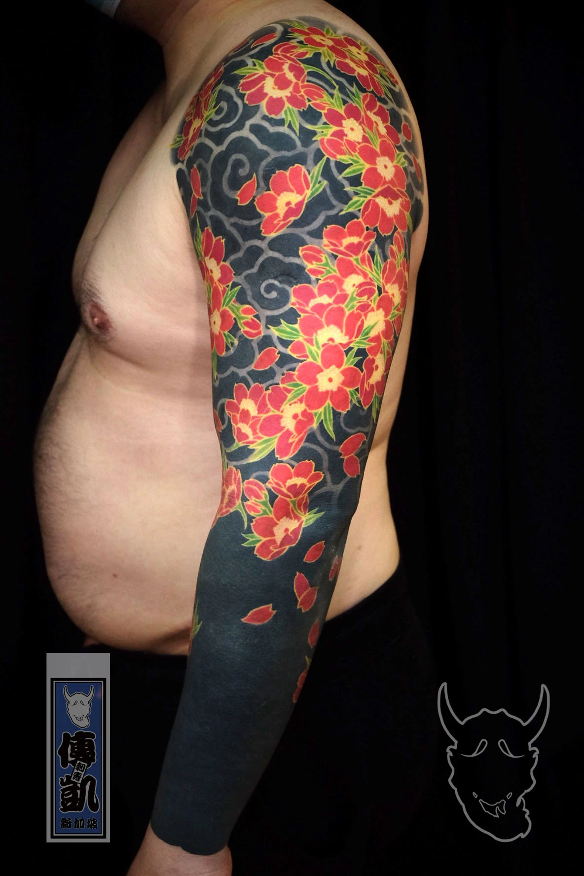 Japanese cherry blossom arm sleeve tattoo featuring sakura flowers and cloud motifs, representing renewal, beauty, and the transient nature of life.