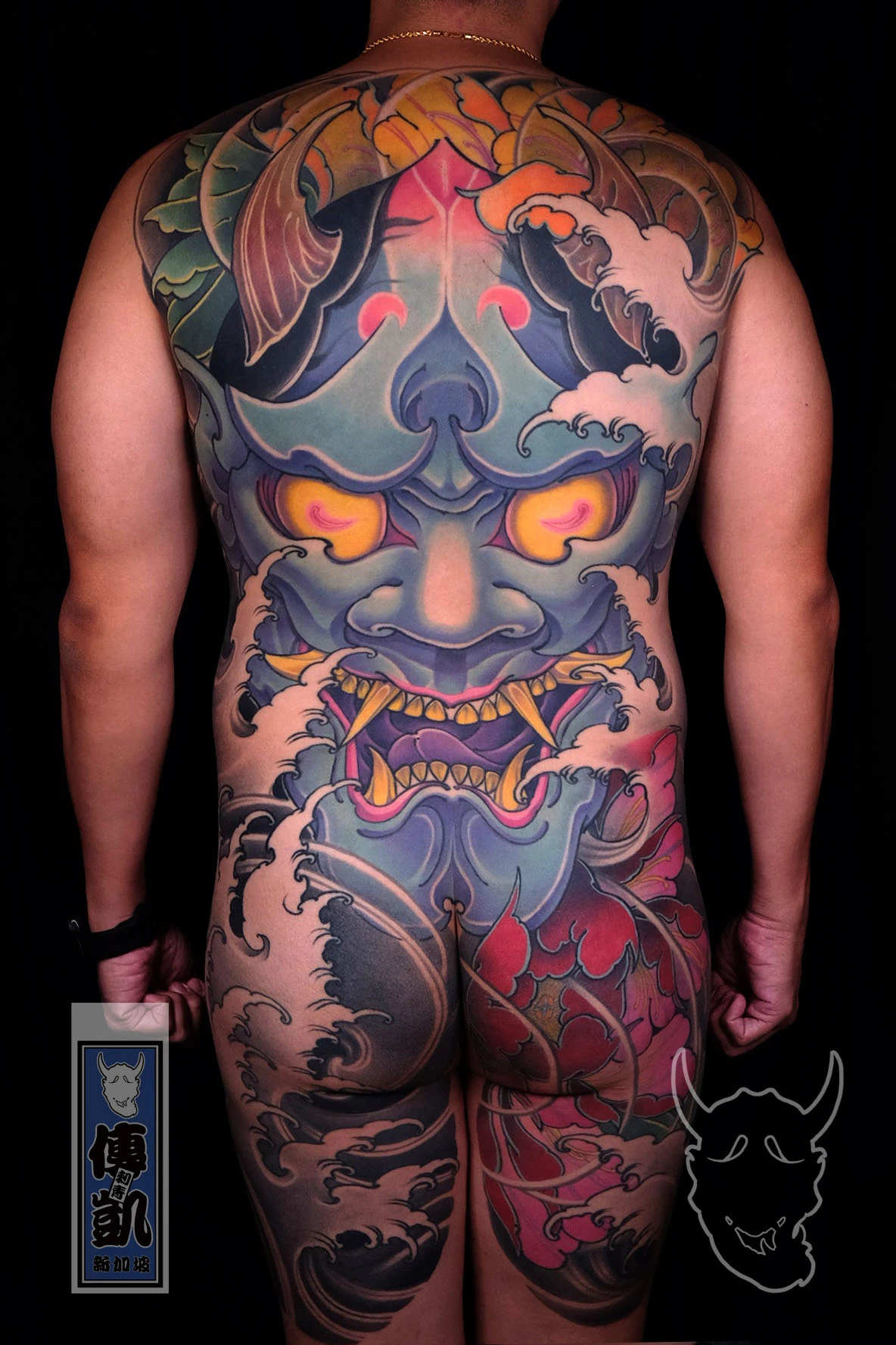 Japanese full back tattoo of a Hannya mask surrounded by peony flowers and waves, representing duality, strength, and transformation in Japanese traditional art style.