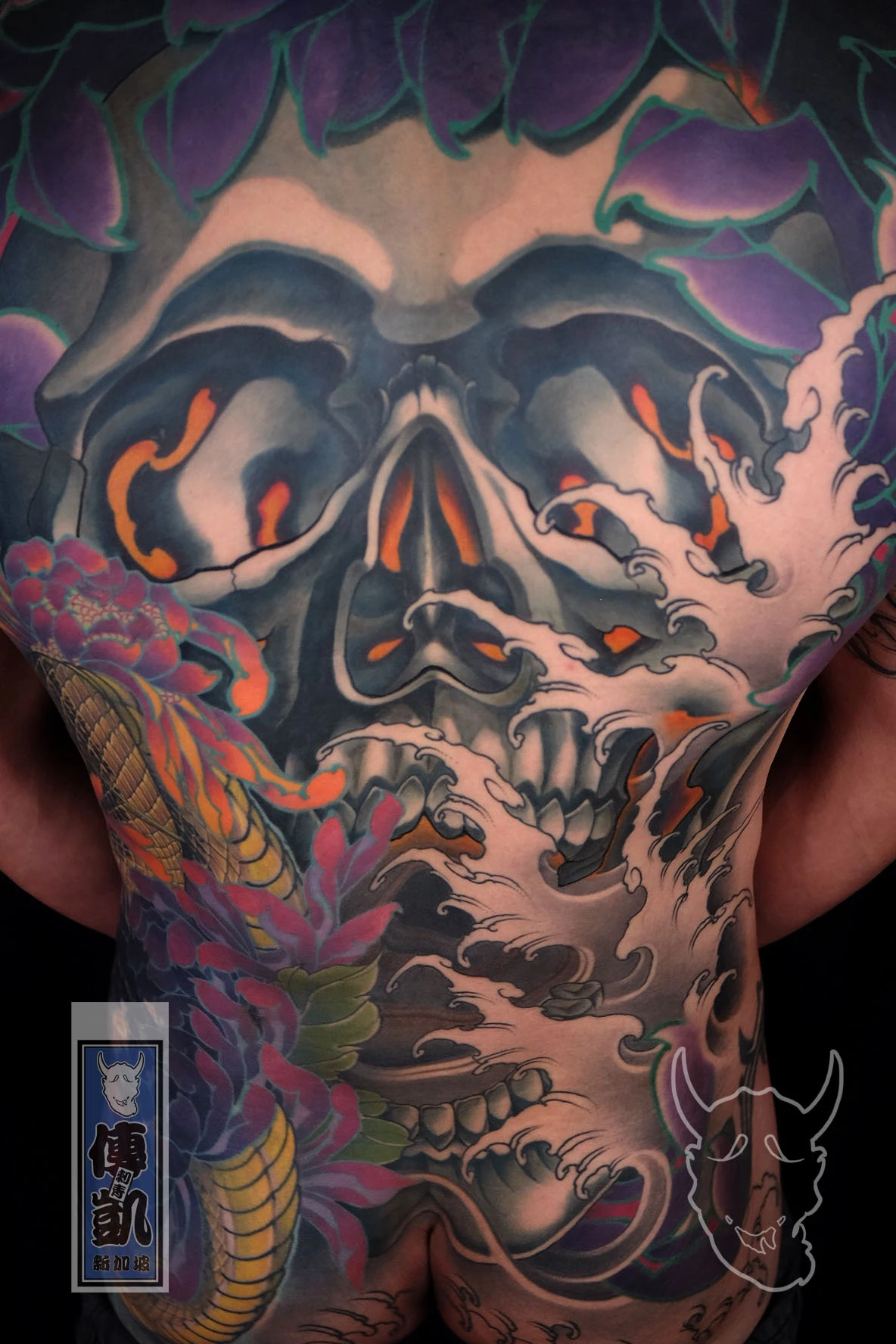 Japanese full back tattoo of a skull with chrysanthemums and wave motifs, representing life, death, and spiritual transformation in traditional Irezumi art.