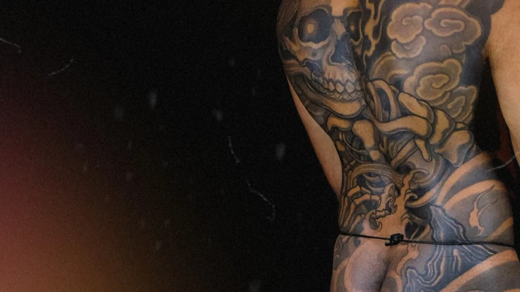 Japanese full back tattoo of a skull enveloped in smoke and waves, representing impermanence, reflection, and spiritual release in traditional Irezumi art.