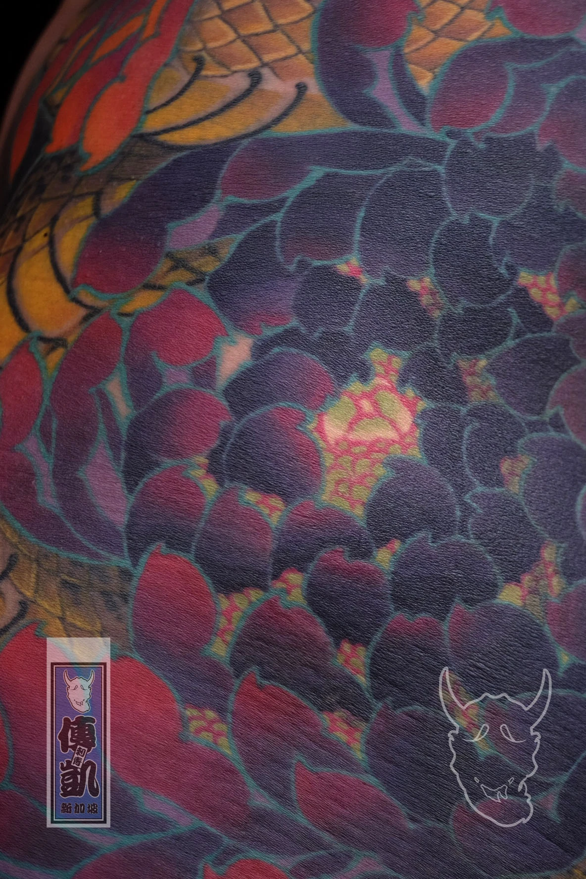 Close up of Traditional Japanese full-body tattoo of a golden snake coiling through red chrysanthemums with rich black and purple shading. Artwork by CK Tattoo Singapore.