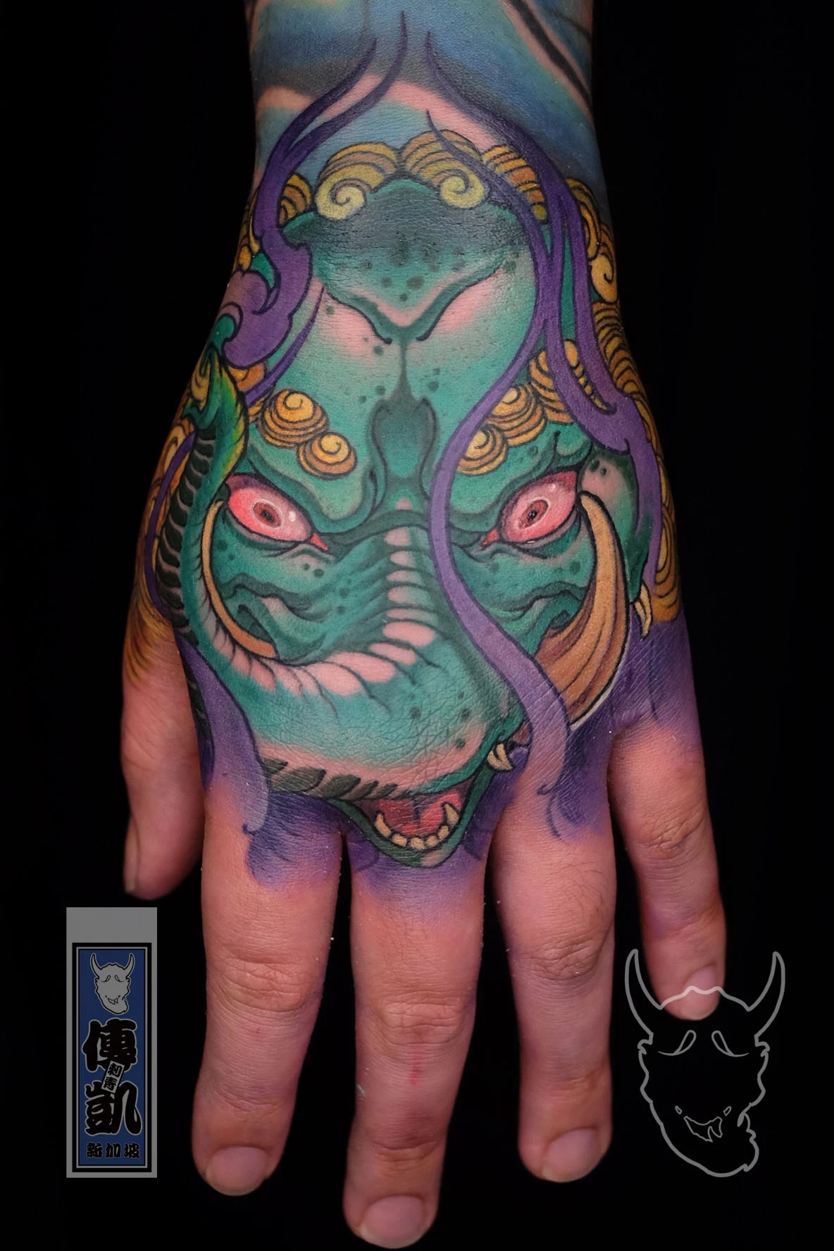 New Traditional Japanese tattoo of a Baku, the dream-eating creature from Japanese mythology, tattooed on the hand in vibrant teal and gold tones with modern composition. Created by CK Tattoo Singapore.