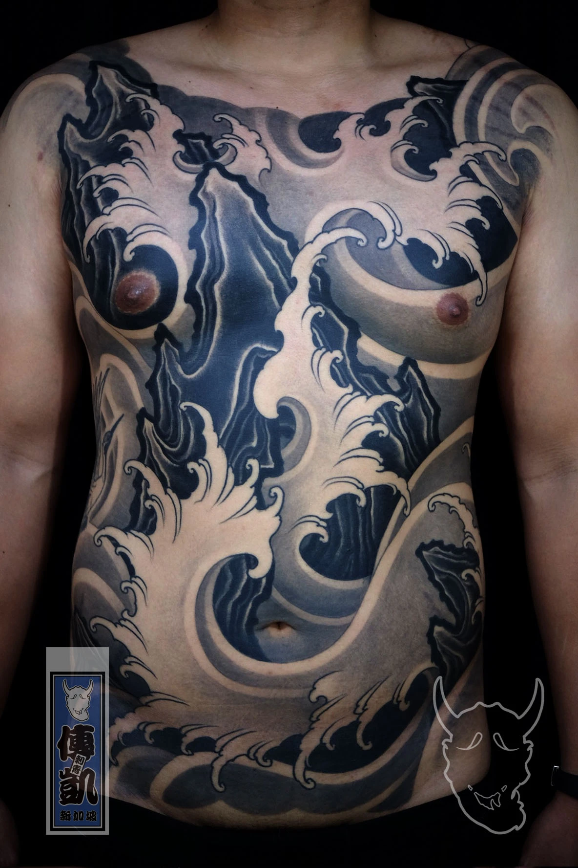 New Traditional Japanese full front tattoo featuring black and grey wave patterns flowing across the chest and torso, symbolizing strength and movement in modern Japanese tattoo art style.