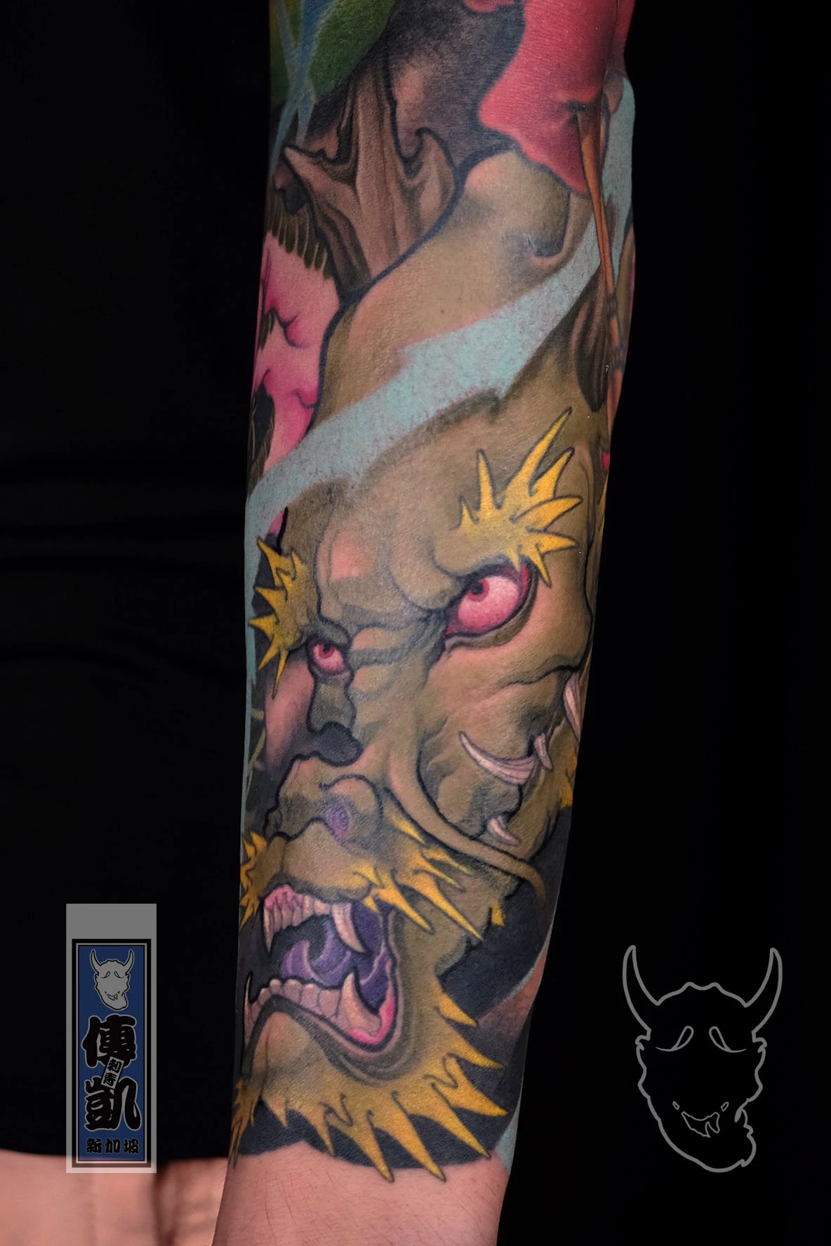 New Traditional Japanese tattoo of a roaring green dragon with yellow whiskers and red eyes inked on the forearm, symbolizing strength and protection. Artwork by CK Tattoo Singapore