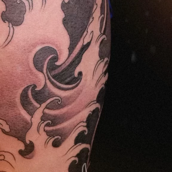 New Traditional Japanese leg tattoo in black and grey with flowing wave patterns, symbolizing strength and fluid motion. CK Tattoo Singapore.