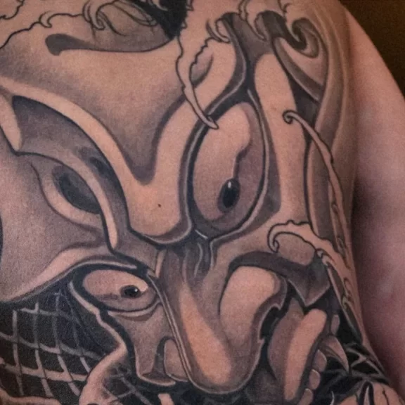 Japanese full back tattoo of a Hannya mask with coiling snakes and waves, in traditional japanese art.