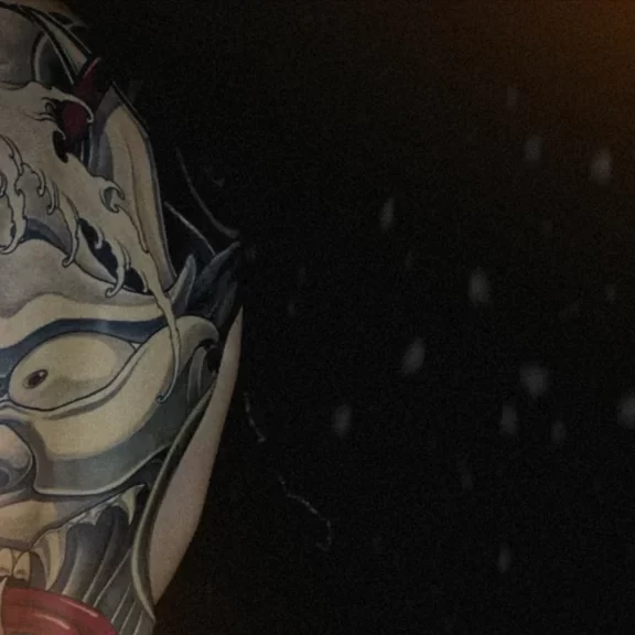 Japanese full back tattoo of a Hannya mask with red ropes and wave motifs, representing emotion, struggle, and transformation in traditional Japanese art.