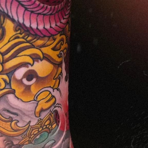 New Traditional Japanese leg tattoo of a red snake entwined around a golden Tibetan skull, symbolizing power and transformation. CK Tattoo Singapore.